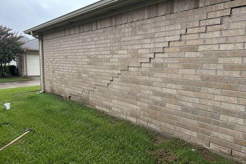 Stair-step cracking through brick veneer at the corner of a house