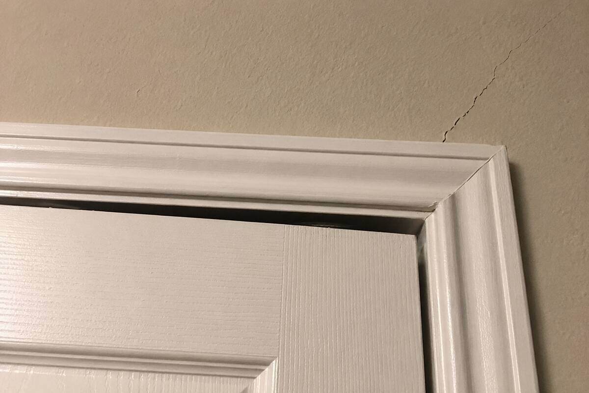 Gap between an interior door and its frame, with a crack running from the frame corner into the wall